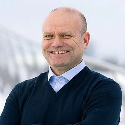 Smilende mann i genser og blå skorte
